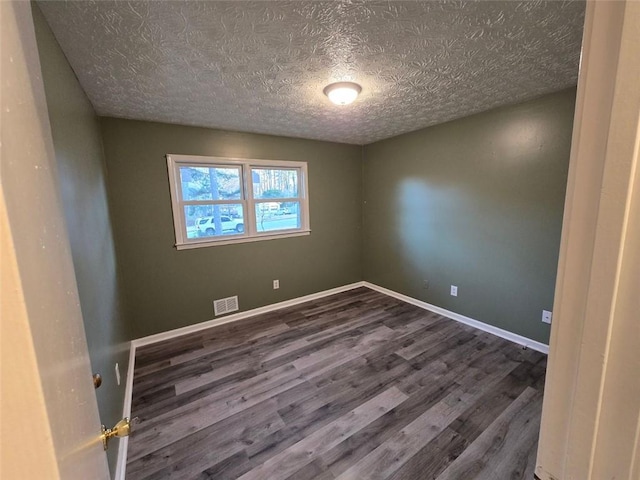 spare room with dark wood-type flooring and a textured ceiling