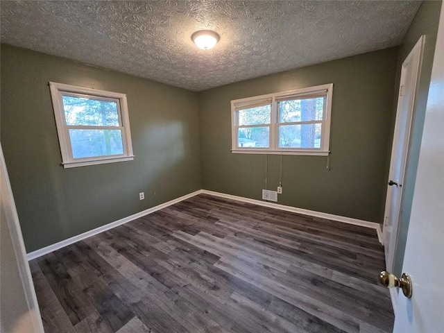 spare room with plenty of natural light, dark hardwood / wood-style floors, and a textured ceiling