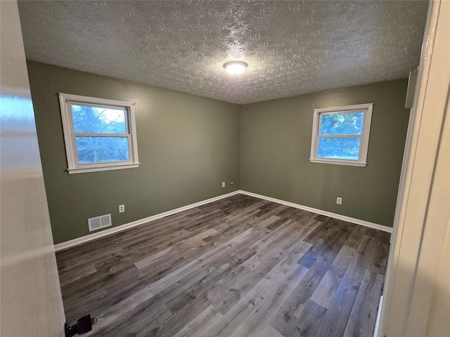 spare room featuring hardwood / wood-style flooring, a wealth of natural light, and a textured ceiling