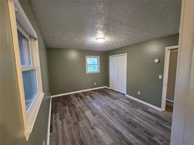 unfurnished bedroom with a textured ceiling, dark hardwood / wood-style flooring, and a closet