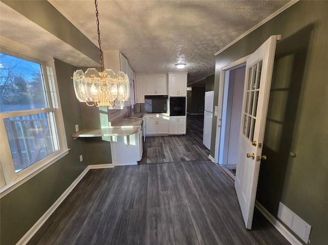 kitchen featuring dark wood-type flooring, white cabinetry, an inviting chandelier, decorative light fixtures, and white fridge