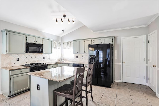 kitchen with light tile patterned flooring, black appliances, light stone counters, and vaulted ceiling