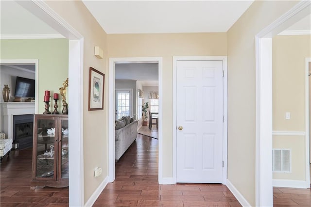 hall with visible vents, baseboards, and wood finished floors