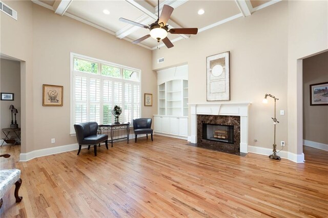 sitting room with light wood-type flooring, a high ceiling, baseboards, and visible vents