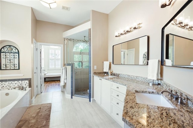 bathroom with a shower stall, double vanity, visible vents, a sink, and a garden tub