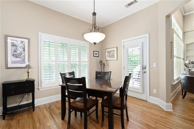 dining room featuring crown molding, visible vents, light wood finished floors, and a wealth of natural light