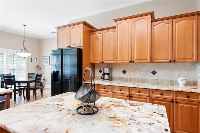 kitchen with black refrigerator with ice dispenser, decorative backsplash, pendant lighting, crown molding, and light stone countertops
