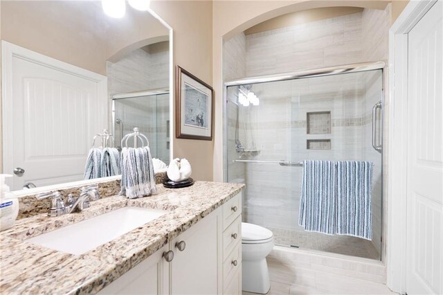 bathroom with toilet, vanity, and a stall shower