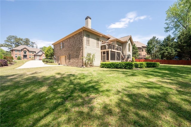 rear view of house featuring a yard, a balcony, a chimney, and fence
