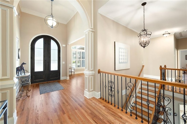 entrance foyer with french doors, wood finished floors, arched walkways, and ornamental molding