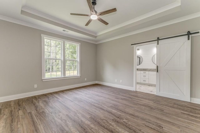 961 Goat Rd NW, Resaca, GA 30735 - unfurnished room featuring a raised ceiling, ornamental molding, a barn door, a ceiling fan, and wood finished floors