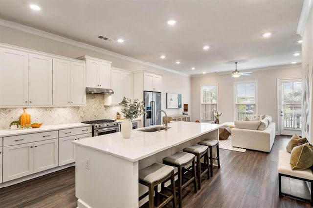 kitchen with white cabinets, a kitchen breakfast bar, high quality appliances, and a center island with sink