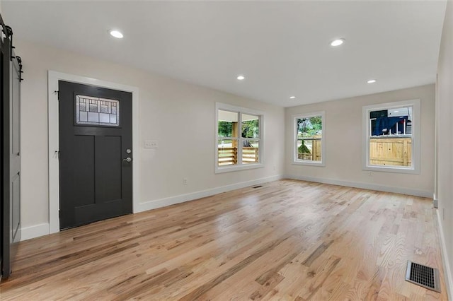 entryway with light hardwood / wood-style floors and a barn door