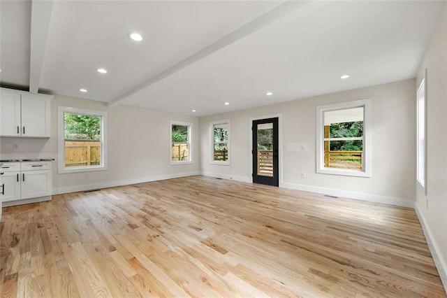 unfurnished living room featuring beamed ceiling and light hardwood / wood-style flooring