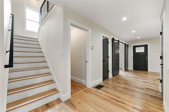 foyer entrance featuring light wood-type flooring and a barn door