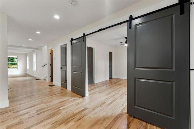 hall featuring light wood-type flooring and a barn door