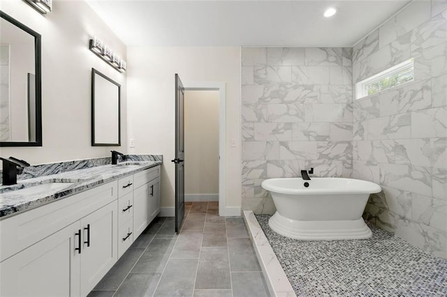 bathroom featuring vanity, a tub to relax in, tile patterned flooring, and tile walls