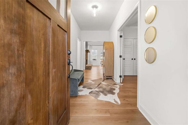 corridor with baseboards and light wood finished floors