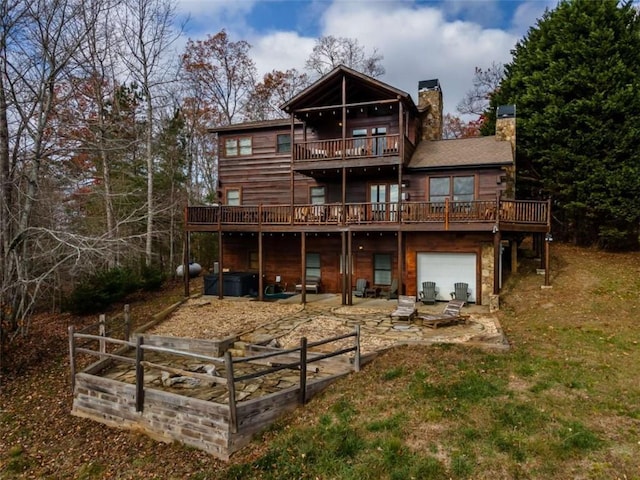 back of house featuring a balcony, a patio, a wooden deck, a yard, and a garage