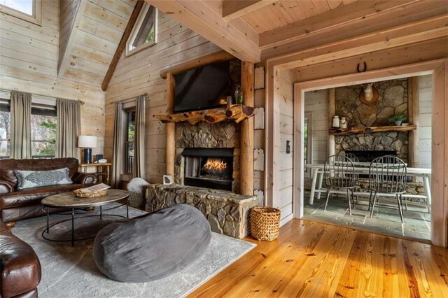 sitting room with wood walls, wooden ceiling, vaulted ceiling with beams, a fireplace, and wood-type flooring