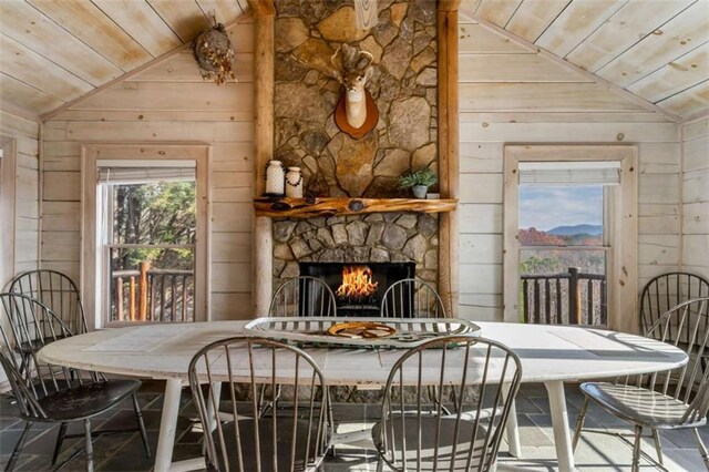 dining area with a stone fireplace, wood ceiling, and vaulted ceiling