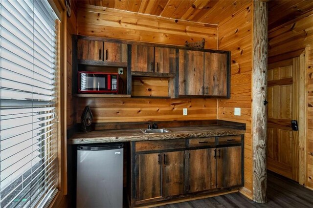 kitchen with stainless steel fridge, wood ceiling, dark wood-type flooring, wooden walls, and sink