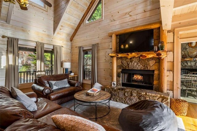 living room with a stone fireplace, a wealth of natural light, wood ceiling, and hardwood / wood-style flooring