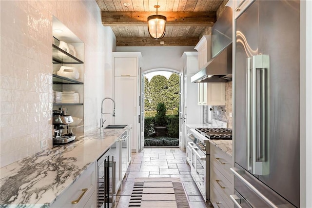 kitchen featuring beam ceiling, sink, wooden ceiling, premium appliances, and decorative light fixtures