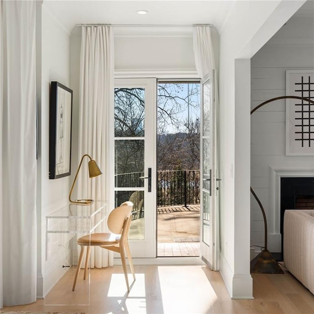 doorway with light hardwood / wood-style flooring and crown molding