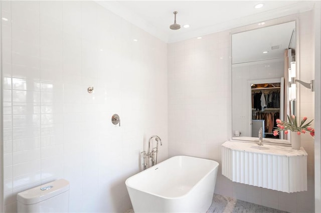 bathroom with a bathing tub, vanity, tile walls, and toilet