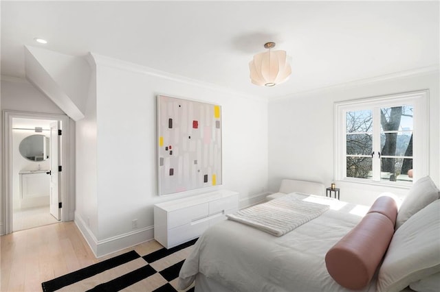 bedroom featuring ensuite bathroom, light hardwood / wood-style floors, and crown molding