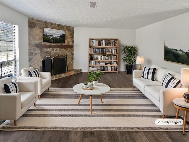 living area featuring visible vents, a fireplace, a textured ceiling, and wood finished floors