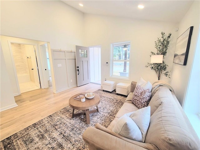 living room with a barn door, high vaulted ceiling, and light wood-type flooring