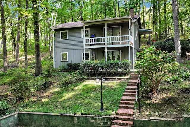 view of front of house with stairway, a chimney, and a front lawn