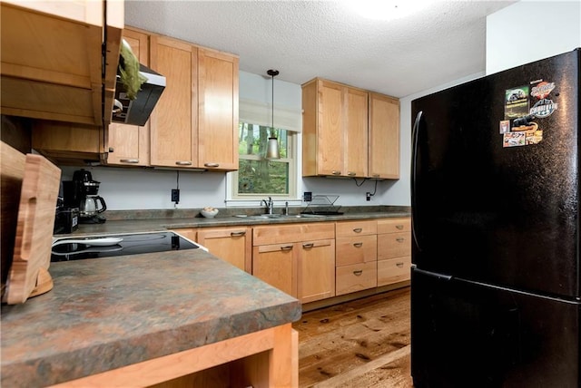 kitchen featuring a textured ceiling, light brown cabinets, a sink, freestanding refrigerator, and dark countertops