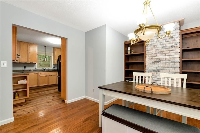 dining room with a chandelier, a textured ceiling, wood finished floors, and baseboards