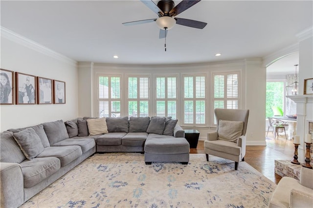 living room featuring hardwood / wood-style floors, ornamental molding, and ceiling fan with notable chandelier