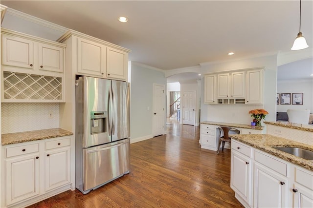 kitchen with light stone countertops, stainless steel fridge with ice dispenser, dark wood-type flooring, crown molding, and hanging light fixtures