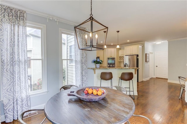 dining space with a notable chandelier, crown molding, and dark hardwood / wood-style floors