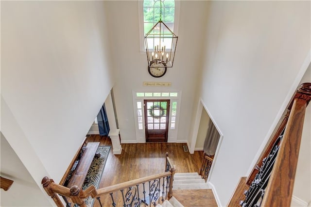 foyer entrance with an inviting chandelier, dark hardwood / wood-style floors, and a high ceiling