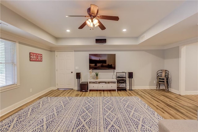 living room with ceiling fan, light hardwood / wood-style flooring, and a raised ceiling