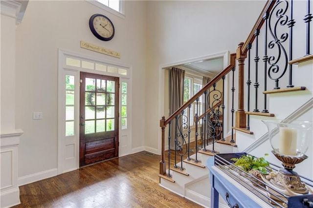 foyer entrance with plenty of natural light, dark wood-type flooring, and a towering ceiling