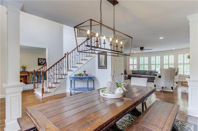 dining area with dark hardwood / wood-style flooring, decorative columns, and ceiling fan with notable chandelier