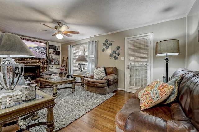 living room featuring wood-type flooring, a brick fireplace, crown molding, and a textured ceiling