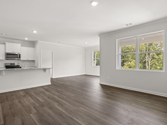 unfurnished living room featuring ornamental molding, dark wood-style floors, recessed lighting, and baseboards