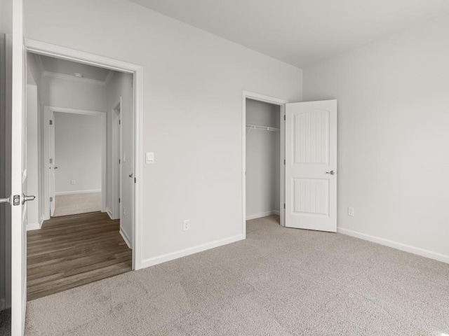 unfurnished bedroom featuring carpet floors, baseboards, a closet, and ornamental molding