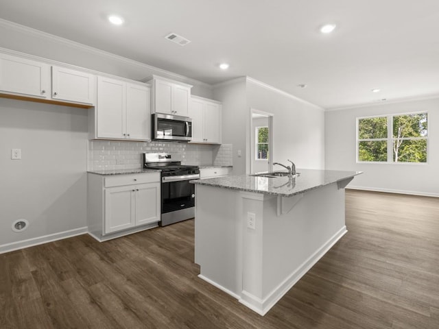 kitchen with appliances with stainless steel finishes, white cabinetry, dark wood finished floors, a kitchen island with sink, and crown molding