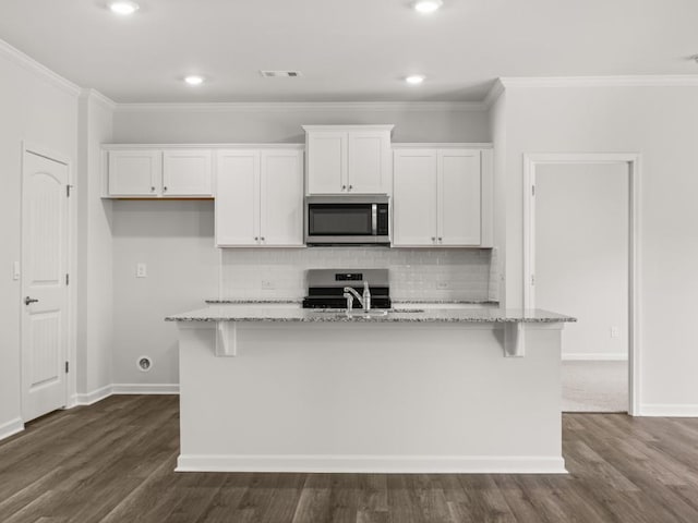 kitchen with stainless steel appliances, white cabinets, a center island with sink, crown molding, and backsplash