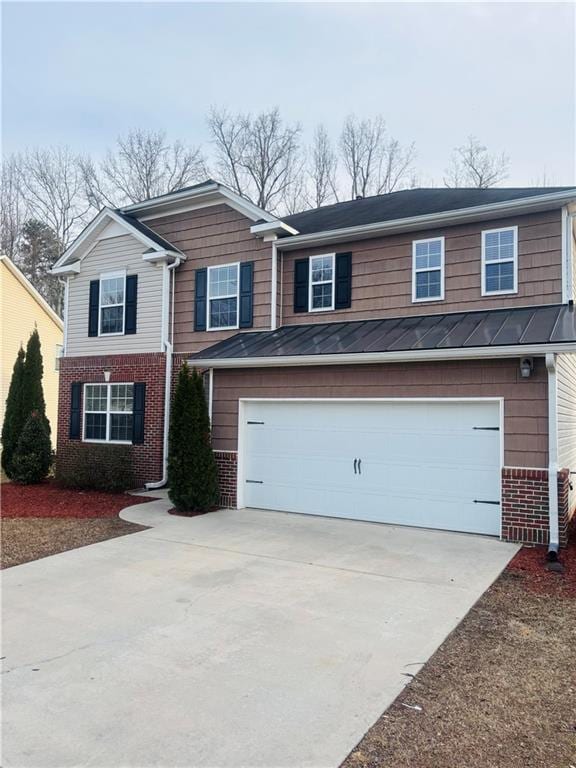 traditional-style home with a standing seam roof, concrete driveway, a garage, brick siding, and metal roof