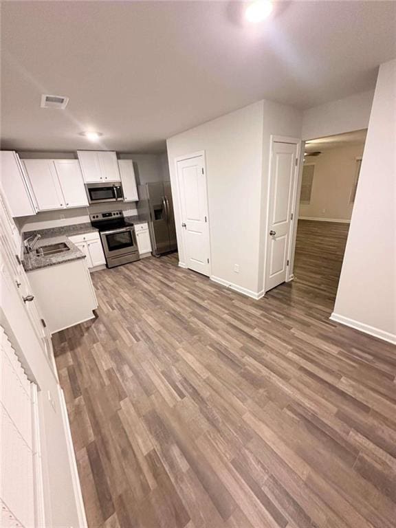 kitchen with hardwood / wood-style flooring, stainless steel appliances, white cabinets, and sink